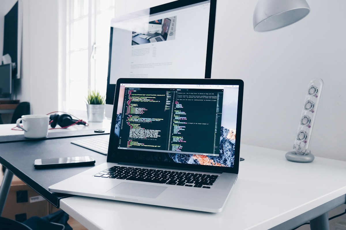 Laptop with code editor open on a desk, representing building a website